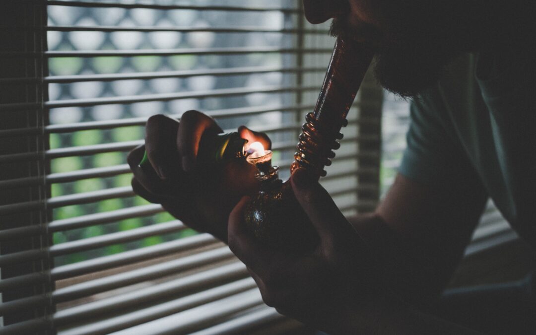 Person Smoking Weed Out Of Bong by Window