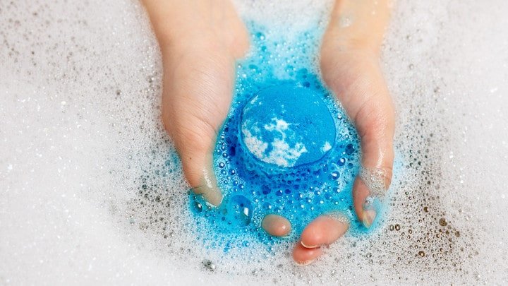 Hands Holding a Bath Bomb into Water