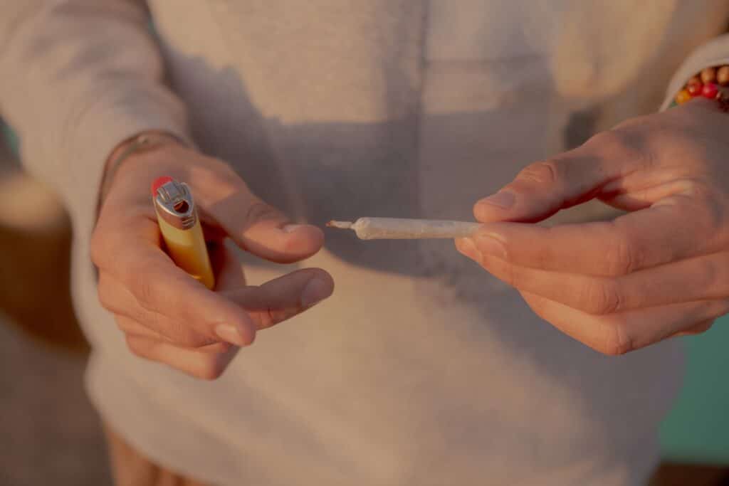 Hands Holding a Cannabis Joint and a Lighter