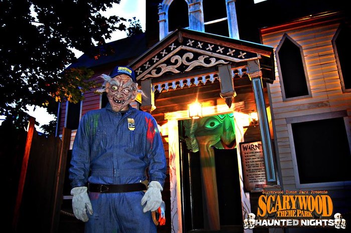 Masked Man Standing in Front of Haunted House at Scarywood