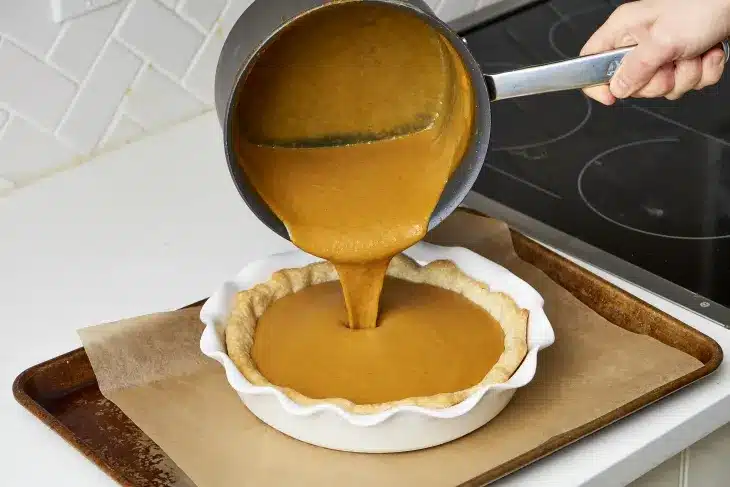 Pumpkin Pie Filling Being Poured Into Crust