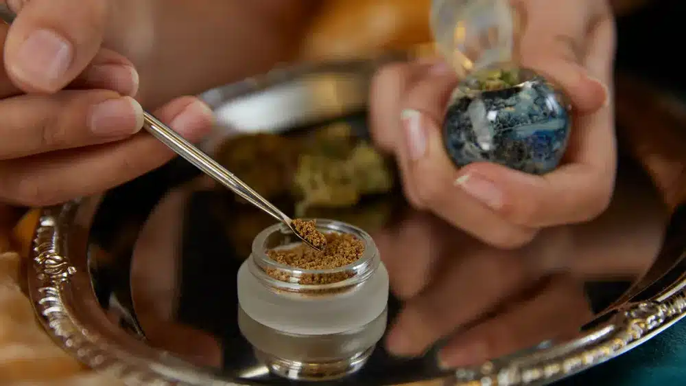 Stoner Scooping Bubble Hash Onto Cannabis Flower in Smoking Pipe