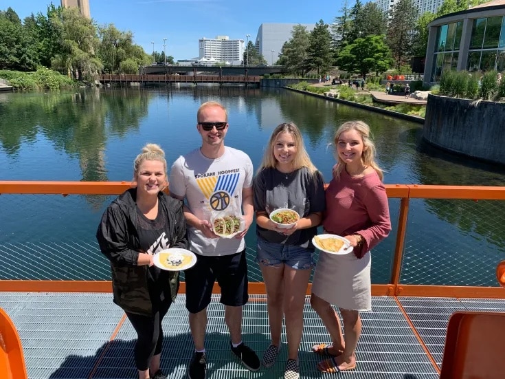 People Posing With Food in Front of the Spokane River