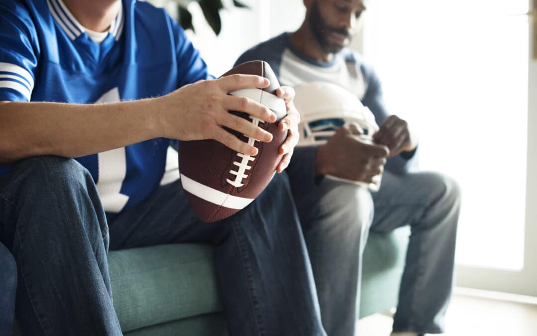 Person Sitting Holding a Football and Playing Fantasy Football