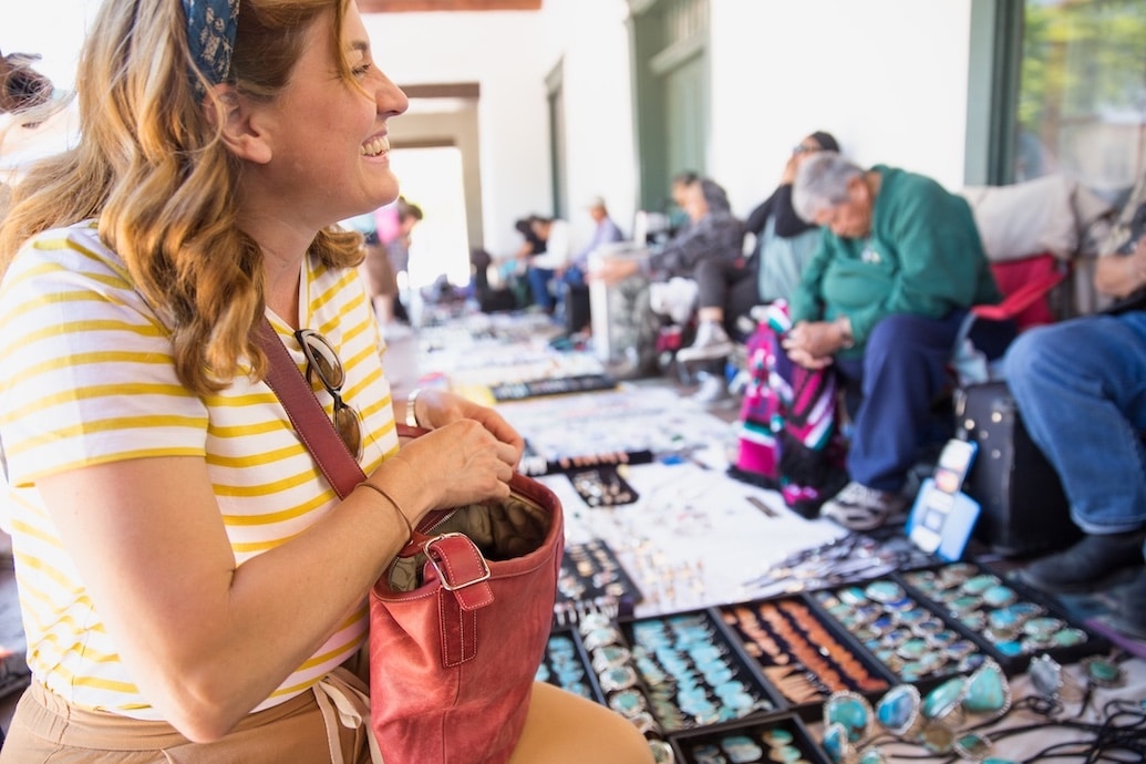 Woman purchasing handmade jewelry at a craft fair market