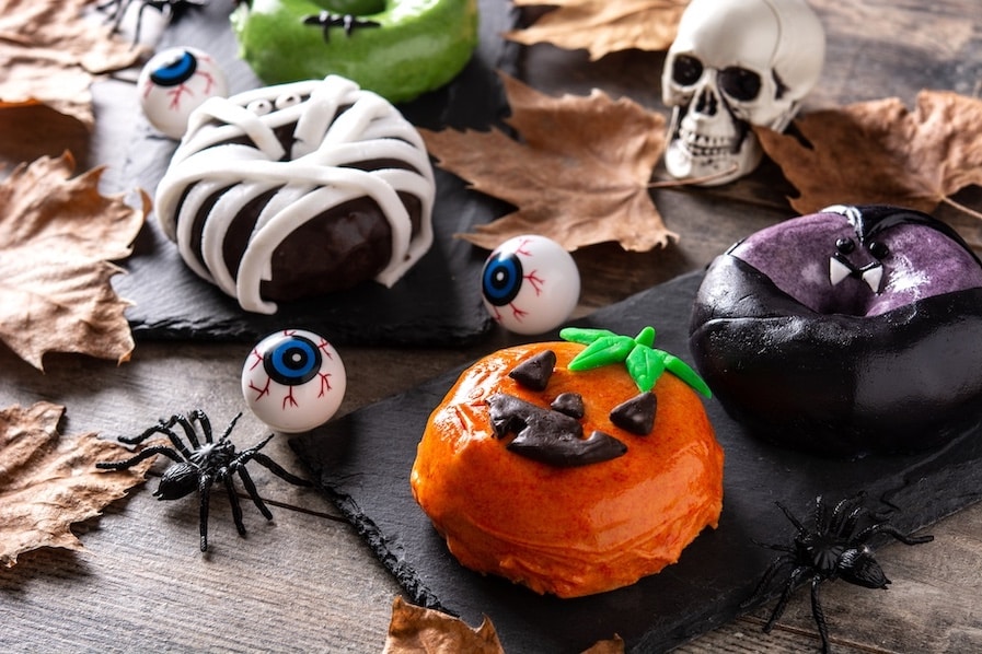 Assortment of Halloween donuts and decorations on wooden table