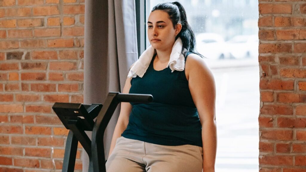 Woman on an exercise bike looking bored