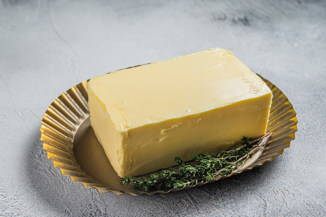 Butter block on steel plate. White background. Top view.