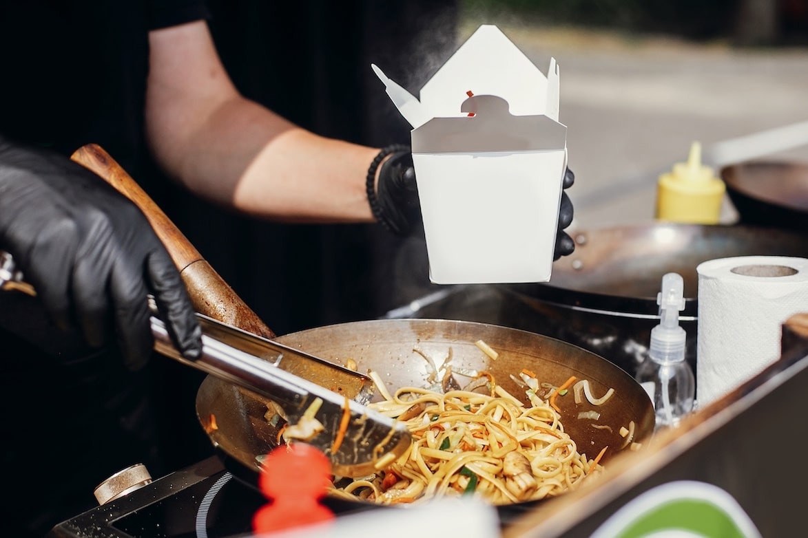 Person cooking fast food noodles and holding take-out container