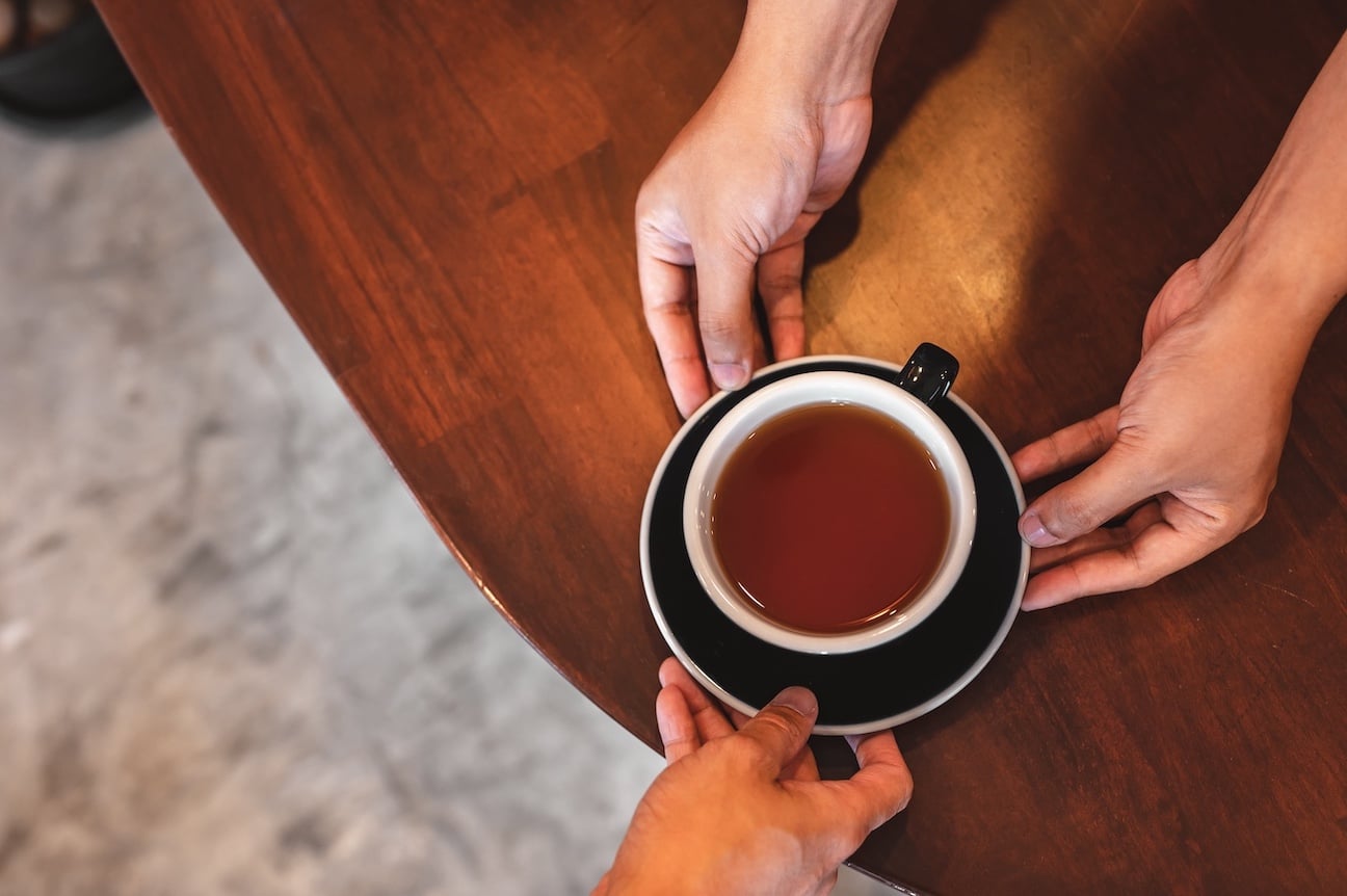 Close up of hands exchanging a cup of tea