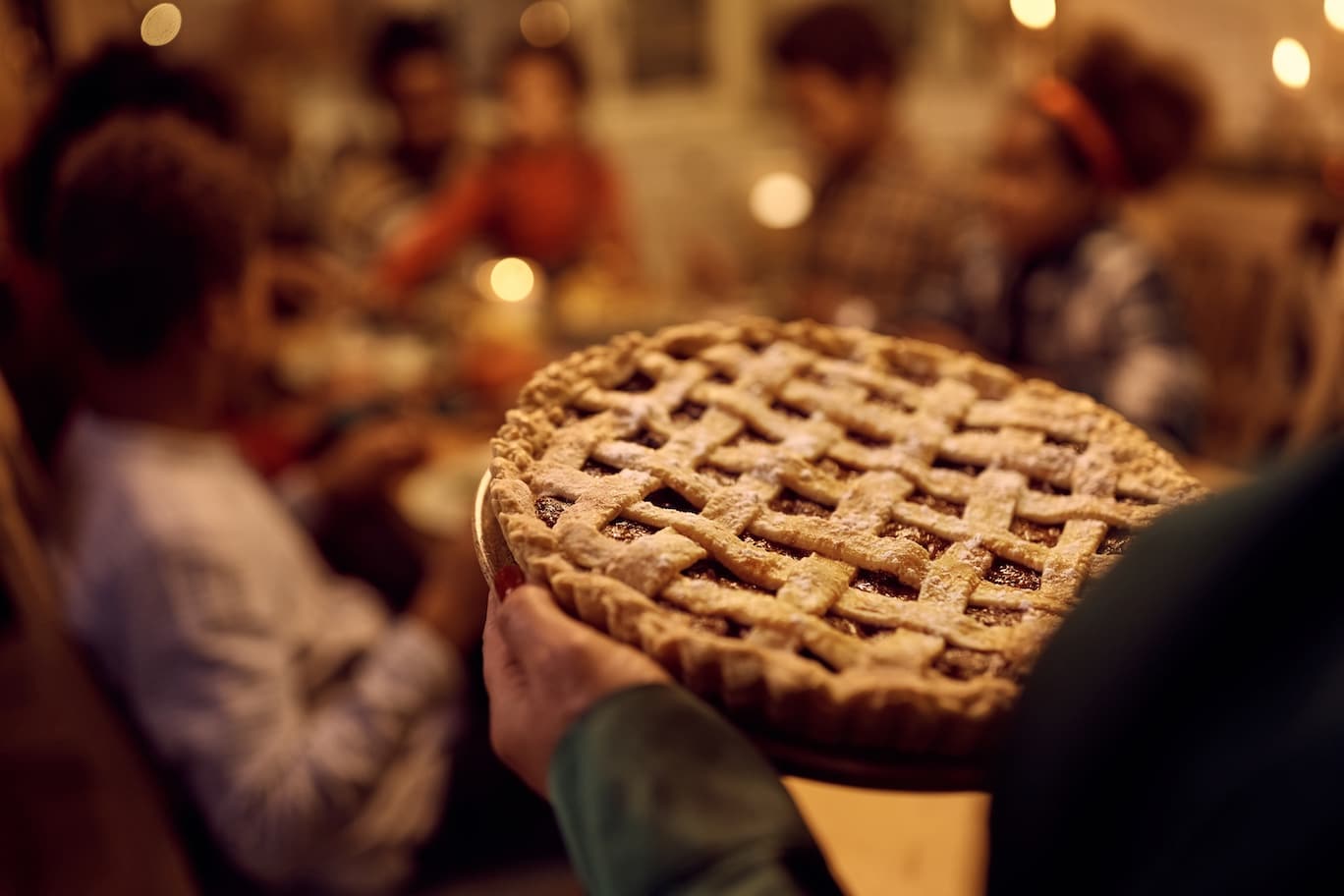 Close up of woman serving pie to her family during Thanksgiving lunch in dining room
