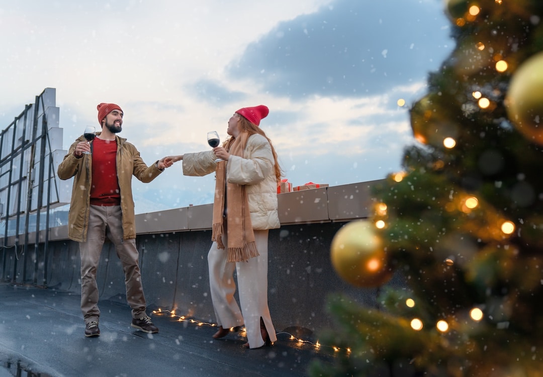 Happy family are celebrating Christmas outdoors. Two young people are having fun, drinking wine.