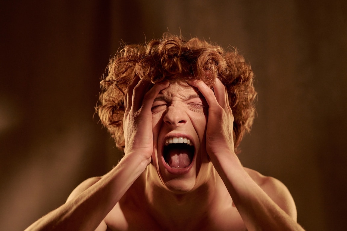Man screaming with hands on face