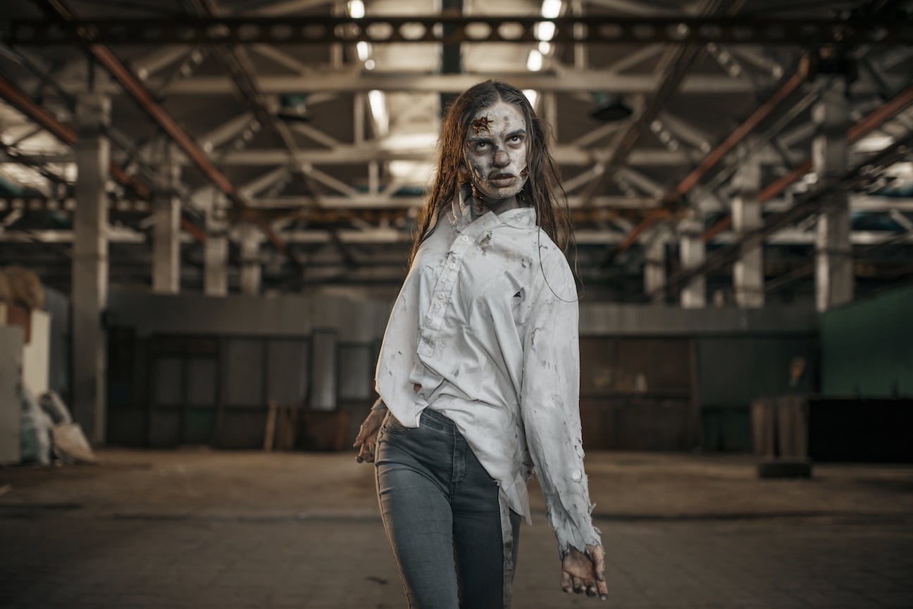 Female zombie walking in abandoned factory, scary place. Horror in city, creepy crawlies attack, doomsday apocalypse, bloody evil monsters