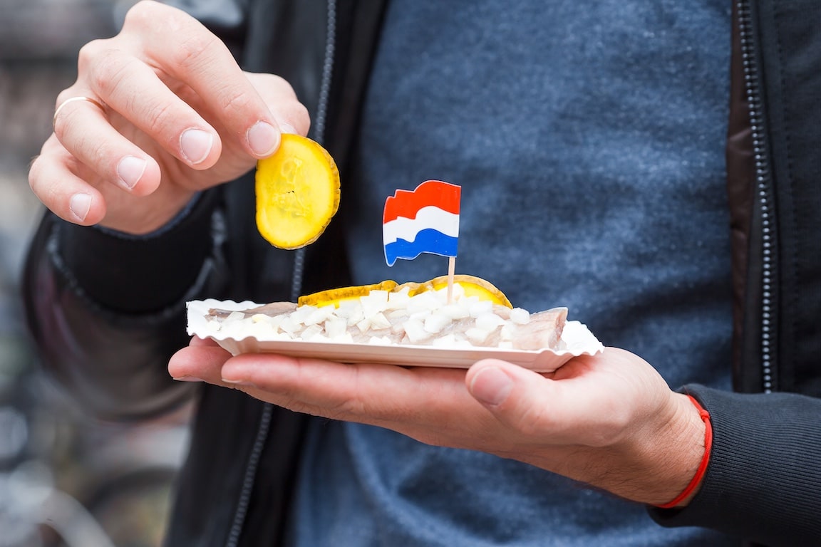 Hand holding a dish with a small Netherlands flag to represent the cannabis strain Dutch Treat
