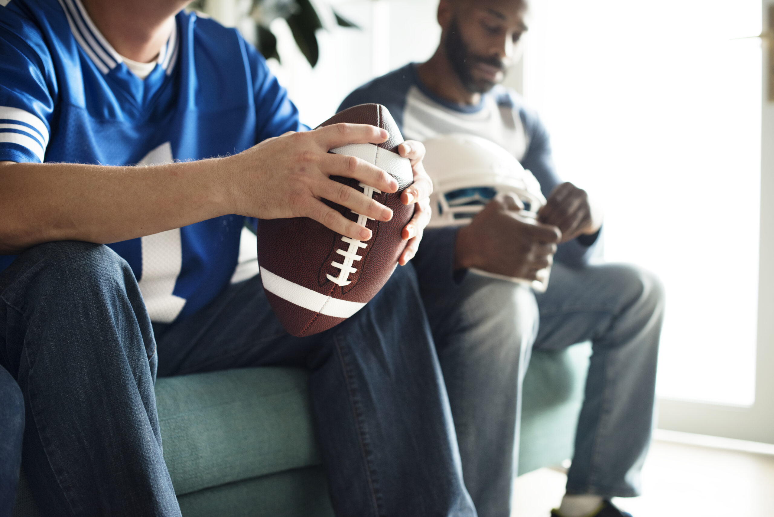 Person Sitting Holding a Football and Playing Fantasy Football