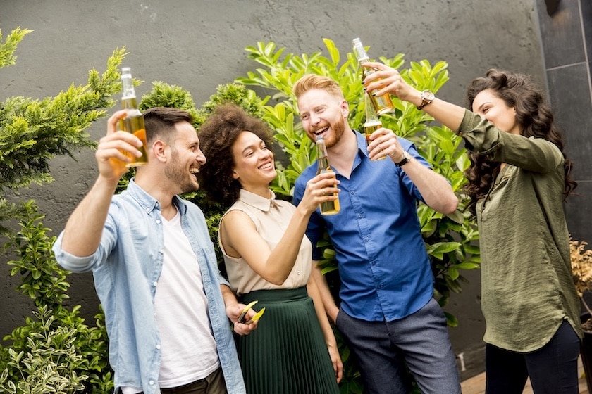 Group of friends having outdoor garden party toast with beer