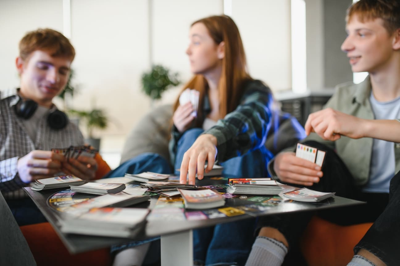 Happy friends enjoying their leisure time, playing a board game and having fun together at home