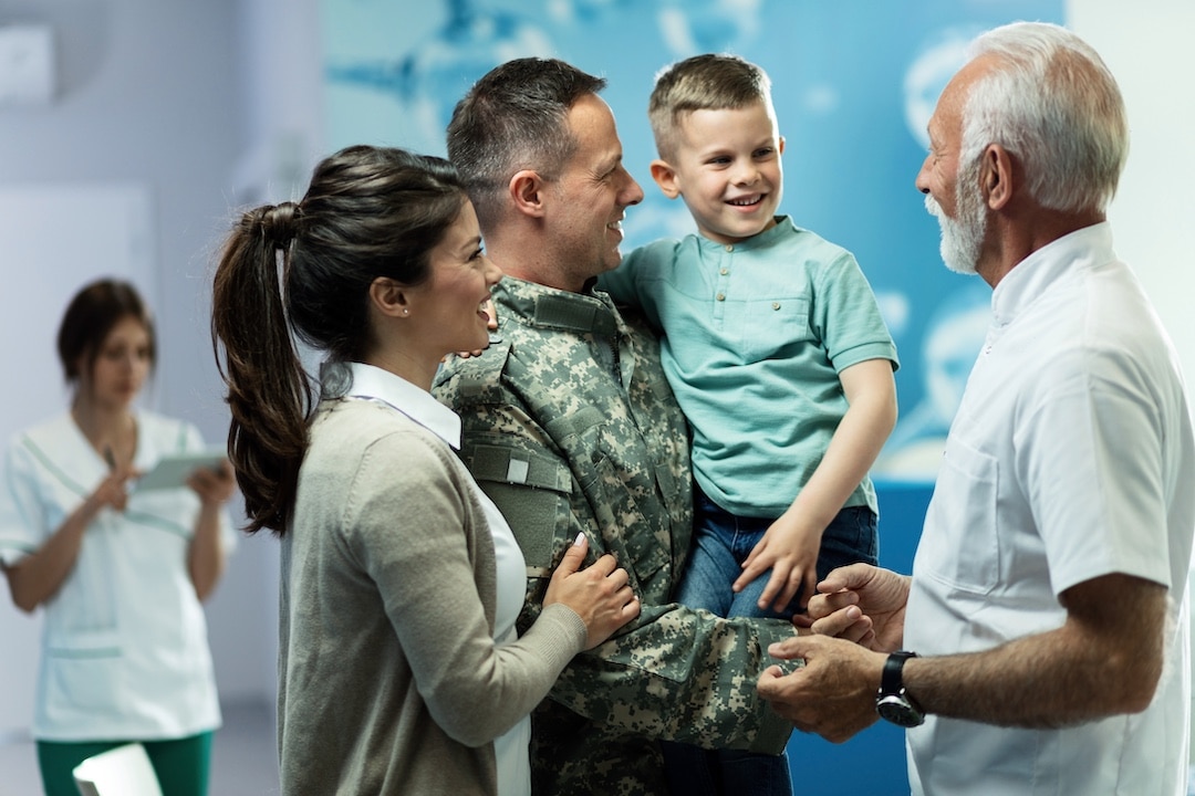 Military veteran with his wife and son while shaking older mans hand