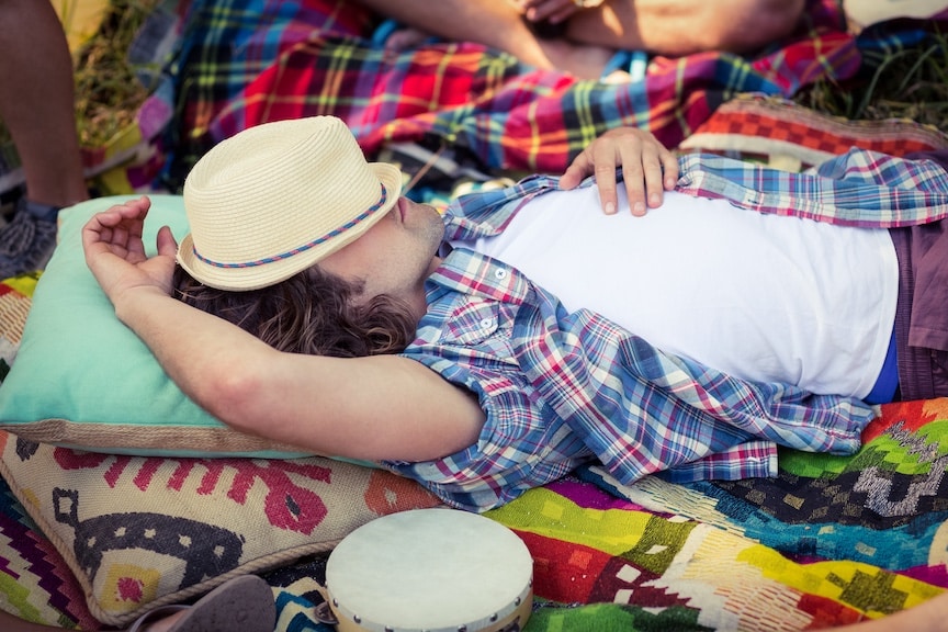 Man sleeping with a hat over his face to represent the strain Cannatonic