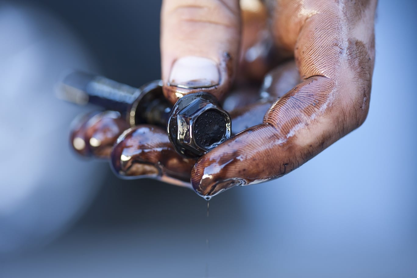Greasy mechanic hand screwing a bolt