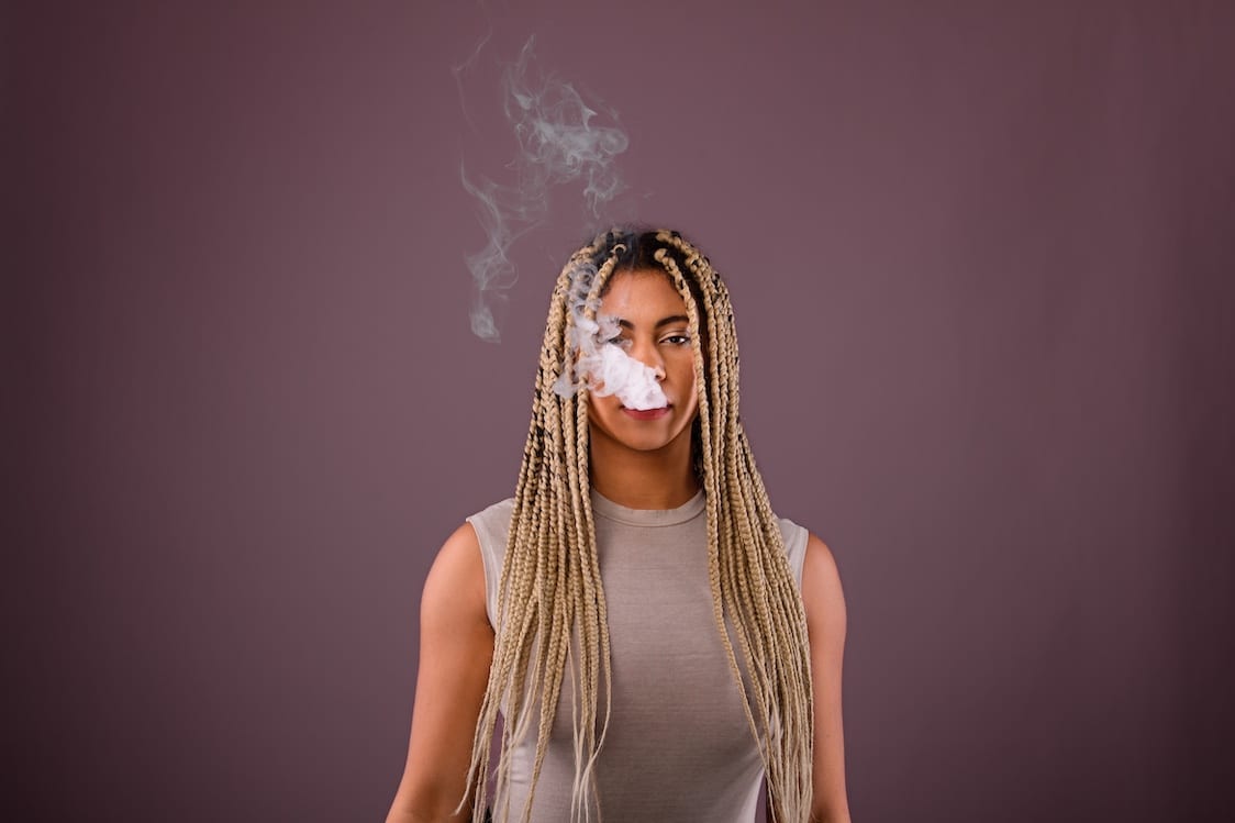 Woman With Smoke Coming Out of Her Mouth Against a Purple Background