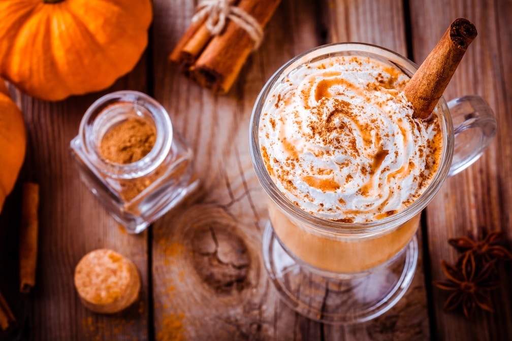 Pumpkin spice latte with whipped cream and caramel on wooden table