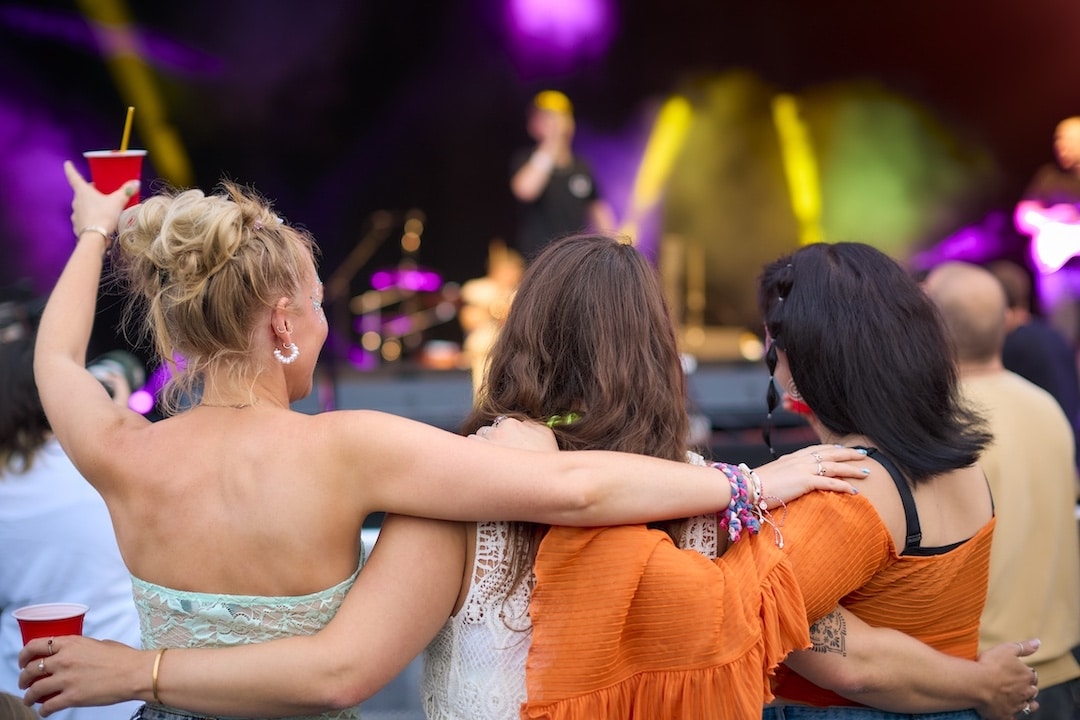 Rear View Of Three Female Friends Dancing At Summer Music Festival Concert