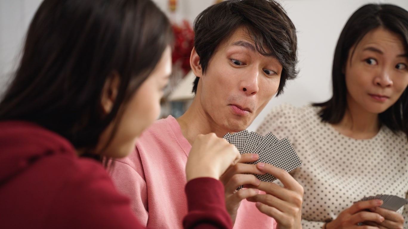 Close-up on people making expressive faces while playing a card game