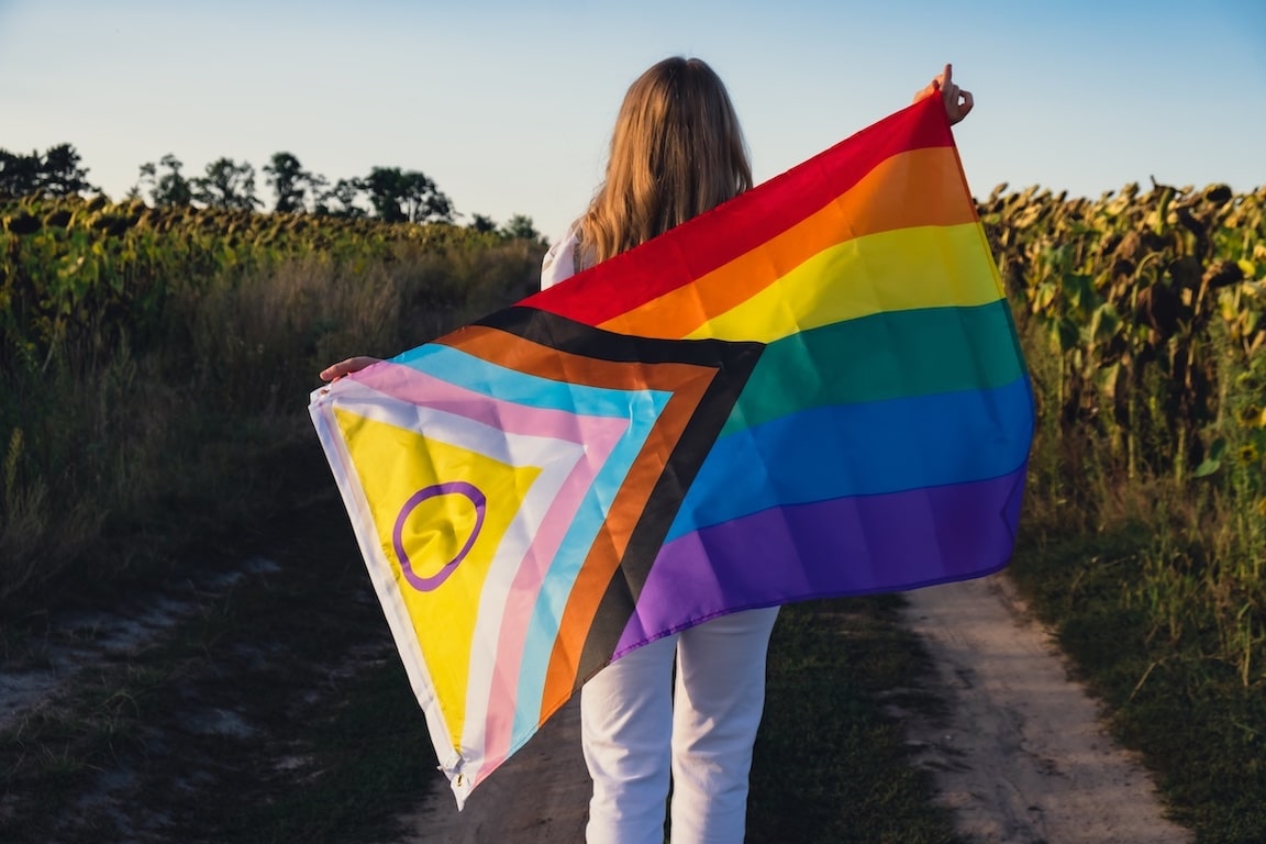 Person Holding the Progress Pride Flag in a Field