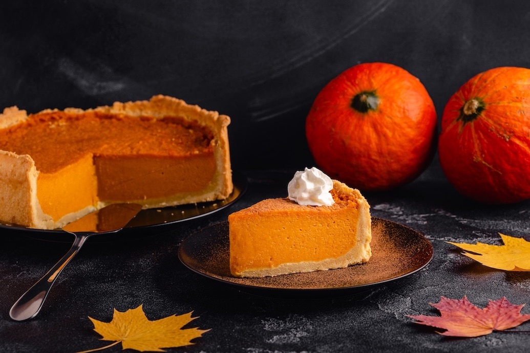 Pumpkin pie surrounded by pumpkins and fall leaves