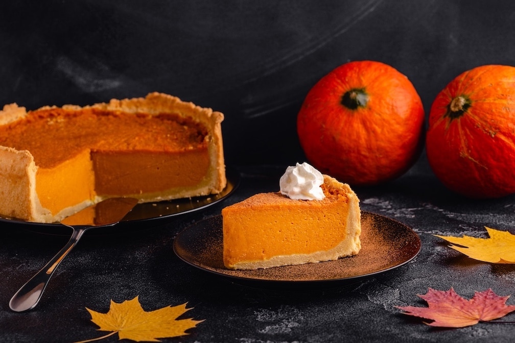 Pumpkin Pie Slice Accompanied by Pumpkins and Autumn Leaves