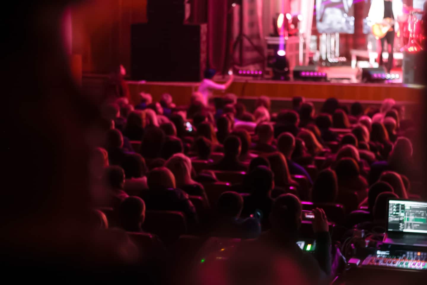 People sitting in a concert hall with pink red lighting
