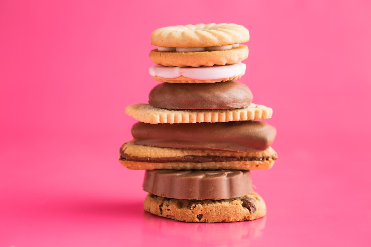Stack of different cookies on a pink backdrop