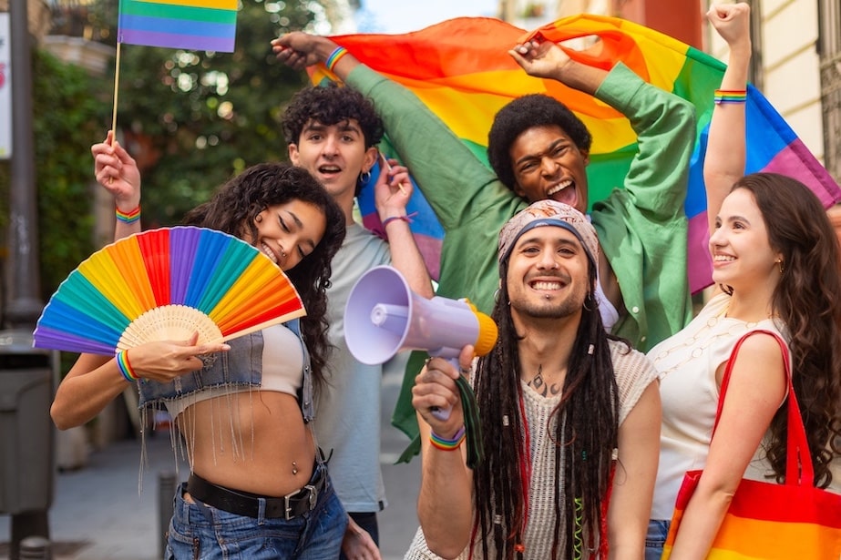 Group of young people holding rainbow flags celebrating LGBTQIA2S+ Pride parade