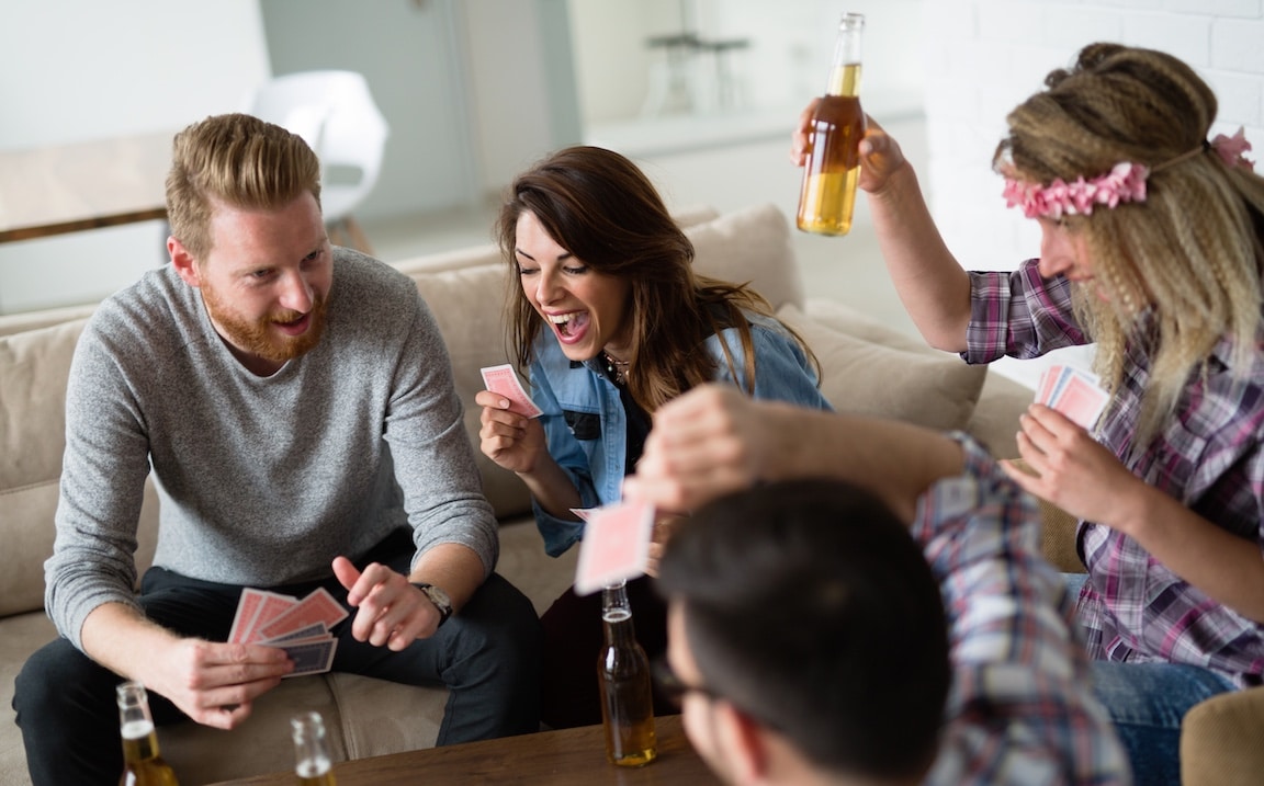 Group of friends playing card game and drinking